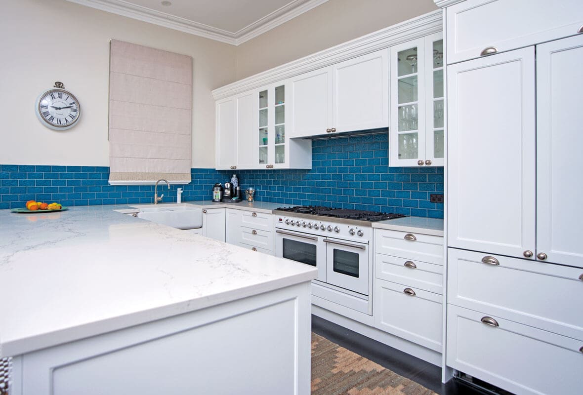 Hamptons style kitchen with white custom made cabinets and blue tiles